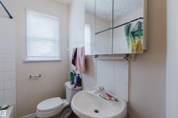 Bathroom featuring a wall-mounted sink, toilet, and a medicine cabinet with mirror doors - 