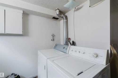 Dedicated laundry area featuring white wall cabinetry, a textured ceiling, and painted white walls - 12223 127 Street, Edmonton, AB - Indoor Photo Showing Laundry Room