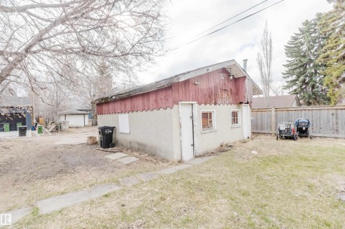 Detached outbuilding with stucco siding and red wood paneling, featuring multiple entry points and windows - 12223 127 Street, Edmonton, AB - Outdoor