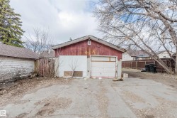 Detached garage with a single overhead door, an asphalt driveway, and a partially fenced perimeter - 