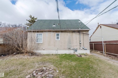 Rear exterior featuring a green shingle roof, stucco siding, and a concrete foundation - 12223 127 Street, Edmonton, AB - Outdoor