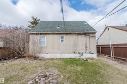 Rear exterior featuring a green shingle roof, stucco siding, and a concrete foundation - 