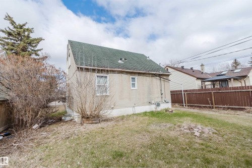 Rear facade featuring stucco exterior, a gabled roofline with green shingles, and multiple windows - 12223 127 Street, Edmonton, AB - Outdoor