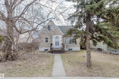 Traditional stucco exterior residence featuring a prominent front gable and a concrete walkway - 12223 127 Street, Edmonton, AB - Outdoor