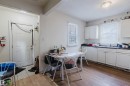 Kitchen area featuring white cabinetry, dark countertops, a stainless steel sink, and wood-finish flooring - 12223 127 Street, Edmonton, AB  - Indoor 