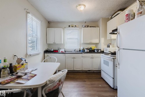 Kitchen featuring wood-finish flooring, white cabinetry, and white appliances - 12223 127 Street, Edmonton, AB - Indoor Photo Showing Kitchen With Double Sink