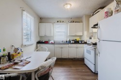 Kitchen featuring wood-finish flooring, white cabinetry, and white appliances - 