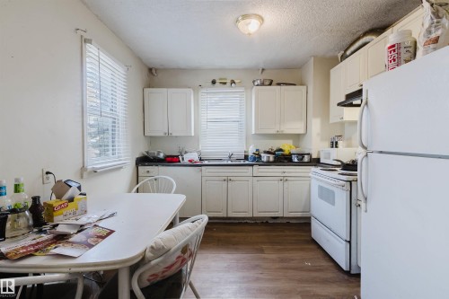 Kitchen featuring white cabinetry, wood-finish flooring, and white appliances - 12223 127 Street, Edmonton, AB - Indoor Photo Showing Kitchen With Double Sink