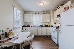 Kitchen featuring white cabinetry, wood-finish flooring, and white appliances - 