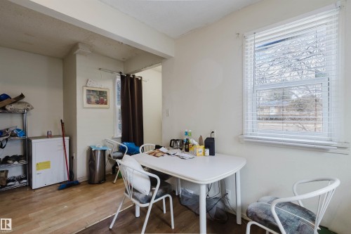 Open-concept room featuring wood-finish flooring, a large window with horizontal blinds, and neutral painted walls - 12223 127 Street, Edmonton, AB - Indoor Photo Showing Other Room