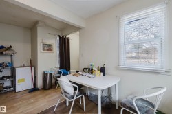 Open-concept room featuring wood-finish flooring, a large window with horizontal blinds, and neutral painted walls - 