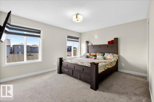 Carpeted room with neutral-toned walls, two windows featuring blinds, and a flush mount ceiling light fixture - 5315 22 Avenue, Edmonton, AB - Indoor Photo Showing Bedroom