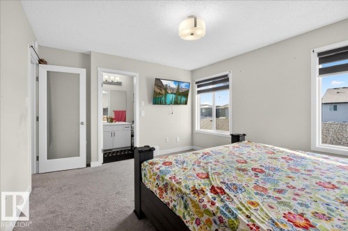Carpeted bedroom with two large windows, a ceiling-mounted light fixture, and a built-in wall-mounted television - 5315 22 Avenue, Edmonton, AB - Indoor Photo Showing Bedroom