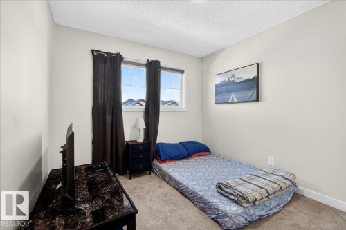 Room featuring neutral wall paint, two windows with dark curtains, and a textured carpet - 5315 22 Avenue, Edmonton, AB - Indoor Photo Showing Bedroom