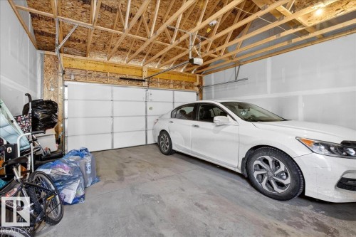 Two-car garage featuring exposed wood beam ceiling, concrete flooring, and an automatic garage door opener - 5315 22 Avenue, Edmonton, AB - Indoor Photo Showing Garage