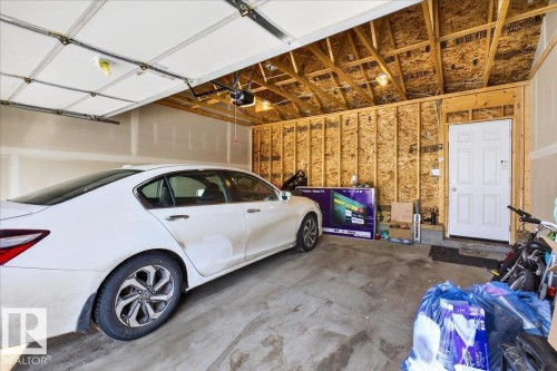 Attached two-car garage featuring a concrete floor, an overhead garage door with an automatic opener, and a white entry door - 5315 22 Avenue, Edmonton, AB - Indoor Photo Showing Garage