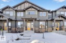 Townhome exterior featuring horizontal siding in a muted green hue, stone veneer accents, and contrasting dark trim - 5315 22 Avenue, Edmonton, AB  - Outdoor With Facade 