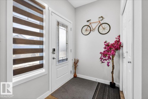 Entryway with wood-finish flooring, a white paneled door featuring a decorative glass insert, and a white framed window with horizontal blinds - 5315 22 Avenue, Edmonton, AB - Indoor Photo Showing Other Room