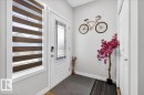 Entryway with wood-finish flooring, a white paneled door featuring a decorative glass insert, and a white framed window with horizontal blinds - 5315 22 Avenue, Edmonton, AB  - Indoor Photo Showing Other Room 