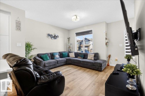 Spacious living area featuring wood-finish flooring, light neutral wall tones, and a large window - 5315 22 Avenue, Edmonton, AB - Indoor Photo Showing Living Room
