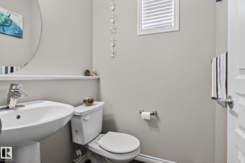 Pedestal sink with chrome faucet, toilet, and a window with blinds - 6912 22 Avenue, Edmonton, AB - Indoor Photo Showing Bathroom