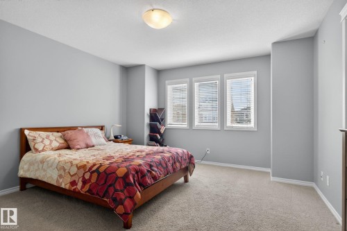 Carpeted room featuring three windows with blinds, a ceiling-mounted light fixture, and light gray walls with white trim - 6912 22 Avenue, Edmonton, AB - Indoor Photo Showing Bedroom