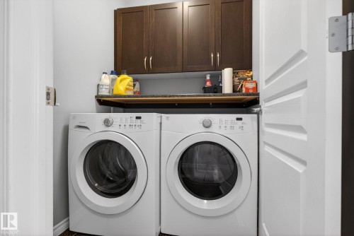 Dedicated laundry area featuring front-loading appliances, a dark wood-finish cabinet, and a functional countertop - 6912 22 Avenue, Edmonton, AB - Indoor Photo Showing Laundry Room