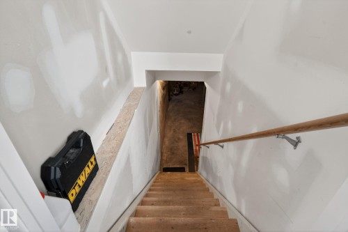 Unfinished basement stairwell with visible drywall work, a wooden handrail, and unpainted wooden stair treads - 6912 22 Avenue, Edmonton, AB - Indoor Photo Showing Other Room