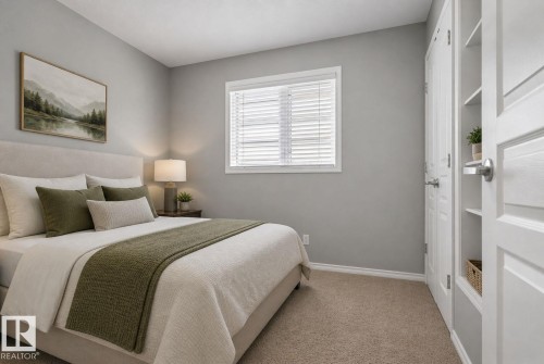 Carpeted bedroom featuring a window with horizontal blinds, light gray walls, white baseboards, and a built-in closet with shelving - 6912 22 Avenue, Edmonton, AB - Indoor Photo Showing Bedroom