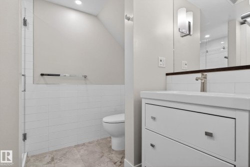 Bathroom featuring a white vanity with integrated sink, brushed nickel faucet, wall-mounted sconce, and recessed lighting - 6912 22 Avenue, Edmonton, AB - Indoor Photo Showing Bathroom