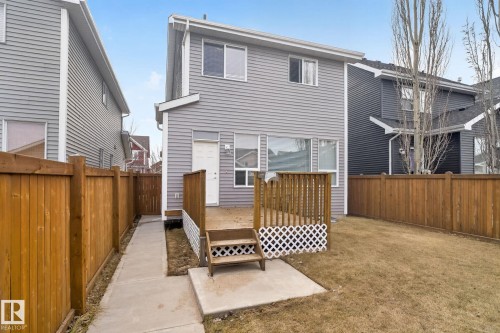 Rear exterior of a two-story residence featuring grey horizontal siding, a wooden deck with lattice accents, and a fenced backyard - 6912 22 Avenue, Edmonton, AB - Outdoor With Exterior