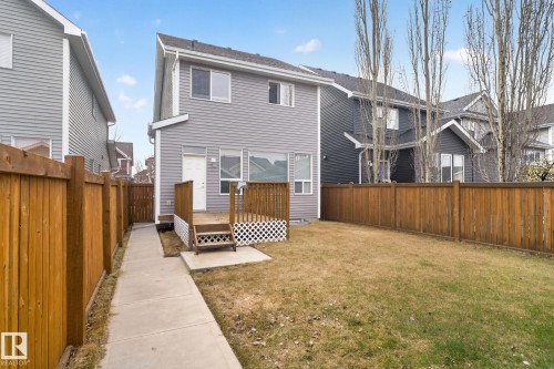Rear exterior featuring a wood deck with lattice skirting, leading to a concrete patio and a grass lawn - 6912 22 Avenue, Edmonton, AB - Outdoor