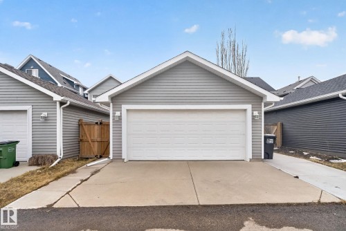 Detached garage featuring a white panel door, gray horizontal siding, and integrated exterior lighting - 6912 22 Avenue, Edmonton, AB - Outdoor