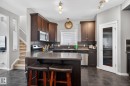 Kitchen featuring dark wood cabinetry, dark stone-finish countertops, stainless steel appliances, and a mosaic tile backsplash - 6912 22 Avenue, Edmonton, AB  - Indoor Photo Showing Kitchen With Double Sink 