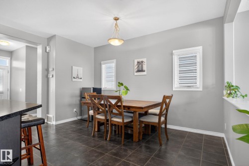 Dining area featuring dark-toned tile flooring, light gray walls, and two windows with blinds - 6912 22 Avenue, Edmonton, AB - Indoor Photo Showing Dining Room