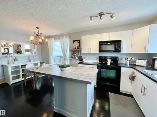 Kitchen featuring dark wood-finish flooring, white cabinetry with silver-tone hardware, and a black range with an overhead microwave - 17936 85 Street, Edmonton, AB - Indoor Photo Showing Kitchen