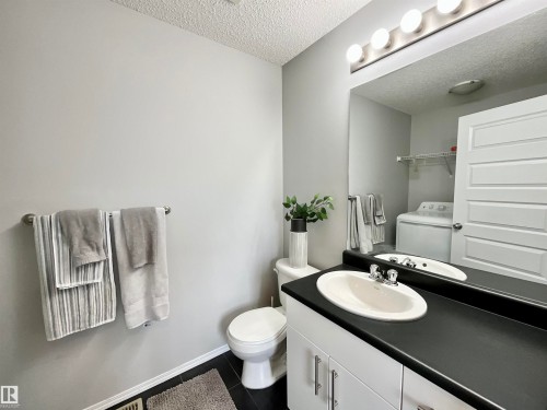 Bathroom featuring a white vanity with a dark countertop, an oval undermount sink, and black tile flooring - 17936 85 Street, Edmonton, AB - Indoor Photo Showing Bathroom