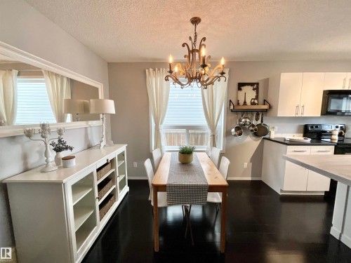 Open-concept dining area featuring dark wood-finish flooring, a decorative chandelier, and light gray wall paint - 17936 85 Street, Edmonton, AB - Indoor