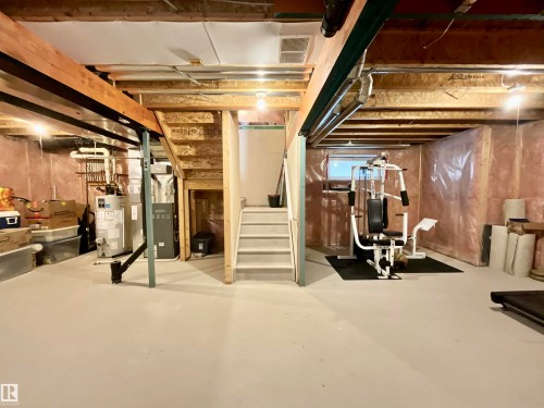 Unfinished basement space featuring exposed wood framing, painted concrete flooring, and a central staircase - 17936 85 Street, Edmonton, AB - Indoor Photo Showing Basement