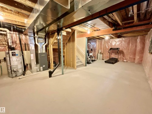 Unfinished basement featuring exposed wood joists, ductwork, and a water heater - 17936 85 Street, Edmonton, AB - Indoor Photo Showing Basement
