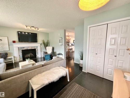 Living area featuring a fireplace with decorative tile surround and white mantel, dark wood-finish flooring, light green wall paint, and white bi-fold closet doors - 17936 85 Street, Edmonton, AB - Indoor Photo Showing Living Room With Fireplace