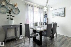 Dining area featuring wood-finish flooring and a contemporary chandelier - 