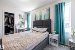 Bedroom featuring an upholstered headboard, a window with natural light, and a built-in closet with shelving and hanging storage - 