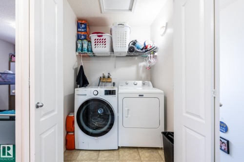 Compact laundry area featuring a front-load washing machine and a top-load dryer - 8644 173 Avenue, Edmonton, AB - Indoor Photo Showing Laundry Room