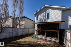 Rear exterior featuring a covered deck with wood railings and dark balusters, light gray siding, and a fenced backyard - 