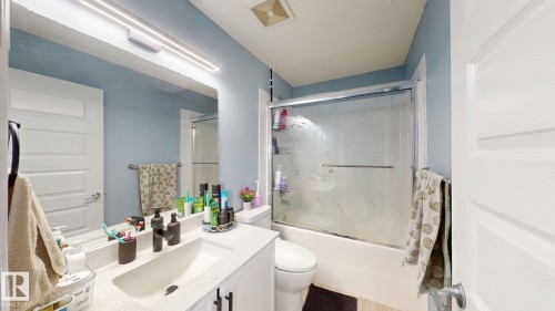 The bathroom features a vanity with a white countertop and an undermount sink, alongside a shower and tub combination with a glass enclosure - 3613 11 Street, Edmonton, AB - Indoor Photo Showing Bathroom