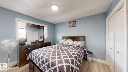 This bedroom features light blue walls, light-toned flooring, and a window with blinds - 3613 11 Street, Edmonton, AB - Indoor Photo Showing Bedroom