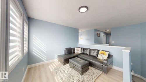 This living area features light-colored flooring, windows with blinds, and light blue walls - 3613 11 Street, Edmonton, AB - Indoor Photo Showing Living Room