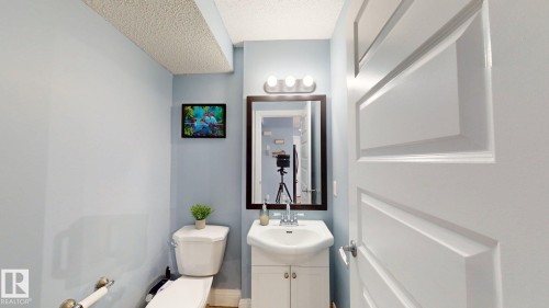 The bathroom features a toilet, a vanity with an integrated sink, and a mirror with overhead lighting - 3613 11 Street, Edmonton, AB - Indoor Photo Showing Bathroom