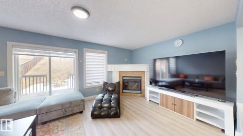 The living space features light-colored flooring, a fireplace with a natural stone surround, and a large sliding glass door - 3613 11 Street, Edmonton, AB - Indoor Photo Showing Living Room With Fireplace